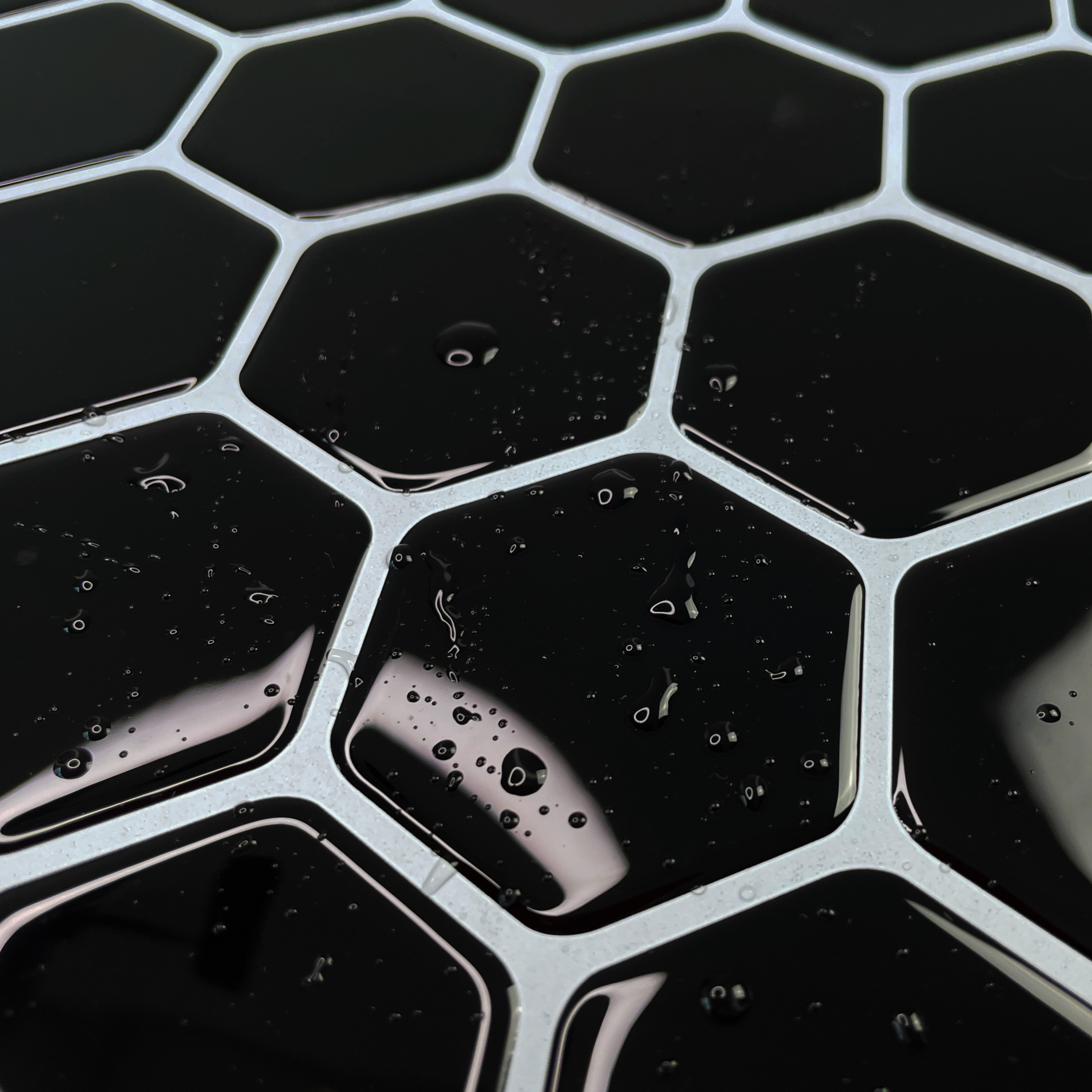 Részletes fénykép a vízzel felázott öntapadós 3D csempéről - fekete hatszögek